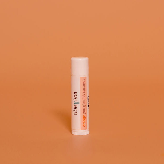 Lip balm tube labeled 'the river' on an orange background